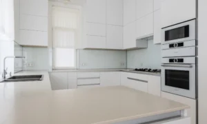 newly renovated small kitchen with white cabinets and electric appliances
